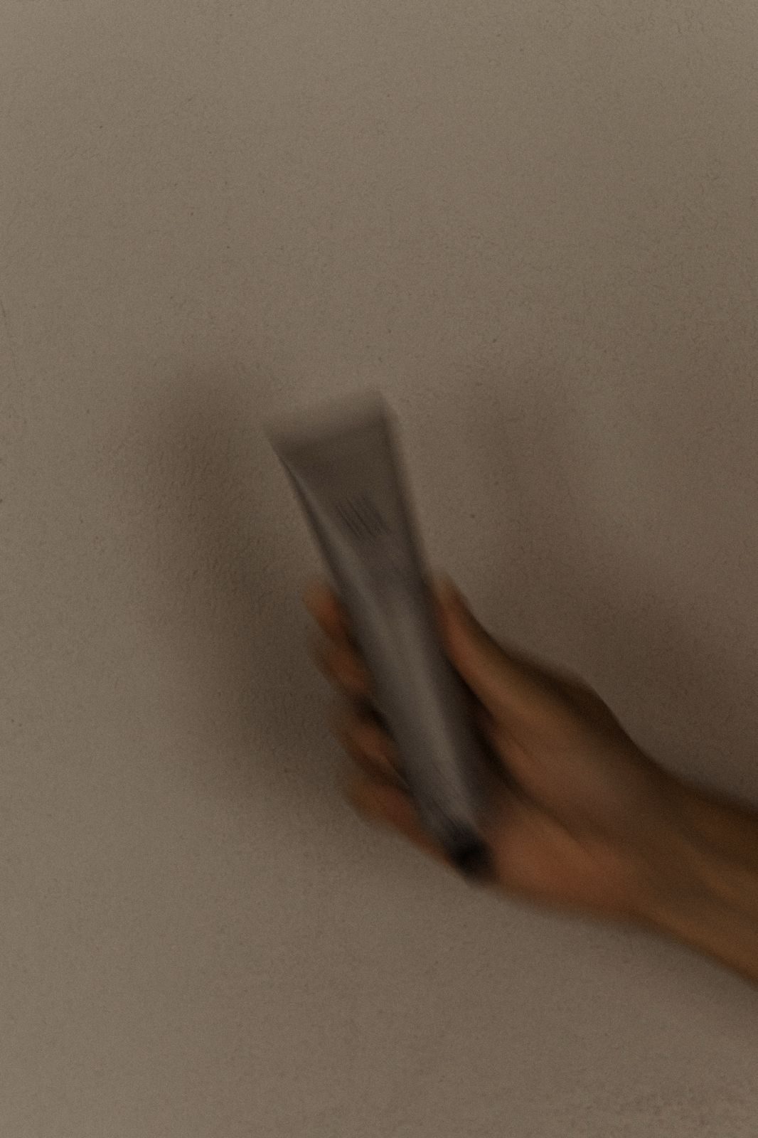 Hand mit einer Farbtube vor ruhiger Wand im Salon Chris Best